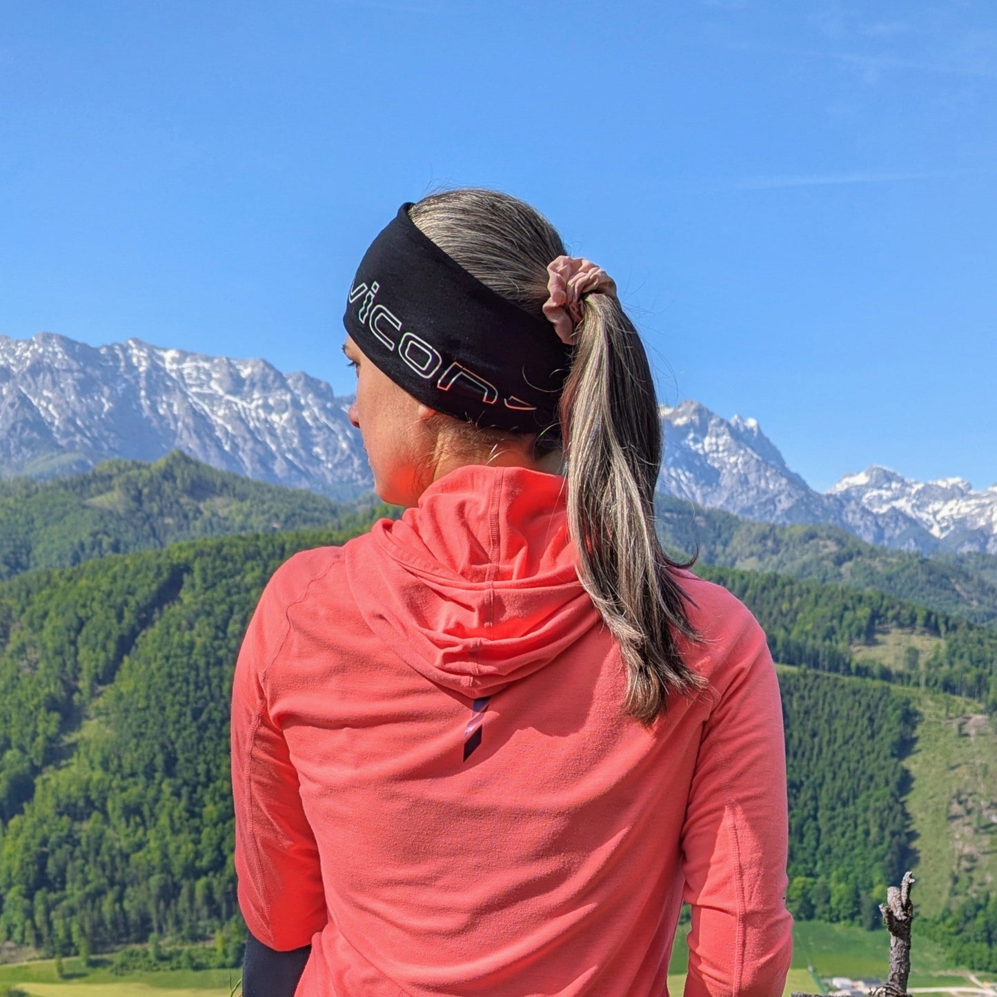 Frau in Sportbekleidung sitzt auf einem Berg.