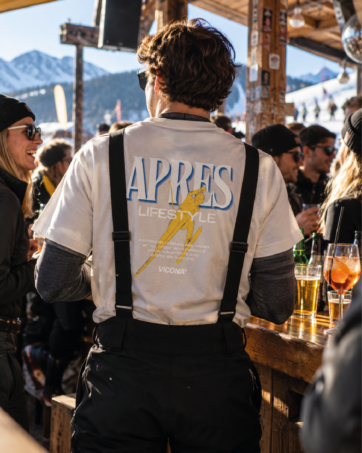 Schirmbar mit Skifahrern die etwas trinken und ein Skifahrer steht im Vordergrund