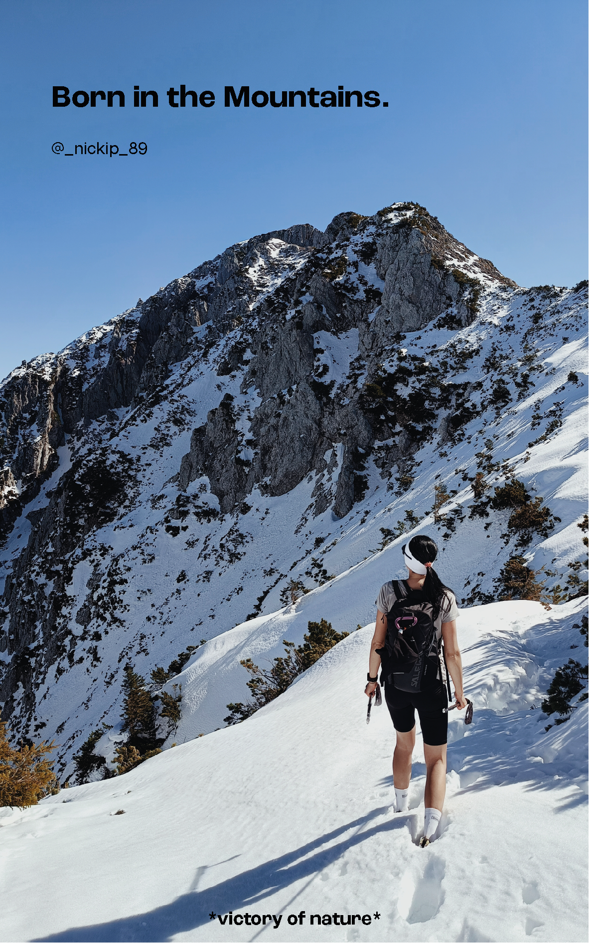 Wanderer der zu einem Berggipffel schaut und dabei im Schnee steht.